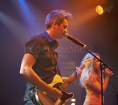 Buy stock photo An expressive frontman singing and playing guitar at a gig. This concert was created for the sole purpose of this photo shoot, featuring 300 models and 3 live bands. All people in this shoot are model released.