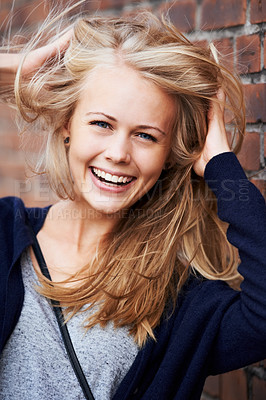 Buy stock photo Portrait, happy and woman with wind in hair by brick wall in city, funny or laugh outdoor. Face, fashion and smile of person, stylish casual clothes and blonde girl with breeze in Switzerland