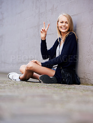 Buy stock photo Portrait of an attractive young woman sitting against a wall