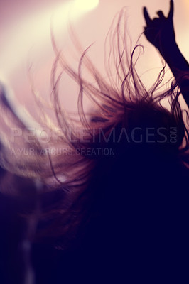 Buy stock photo Rear view of a music fan dancing with her arms raised at a music concert