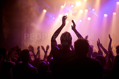 Buy stock photo Rear view of a music fan dancing with her arms raised at a music concert