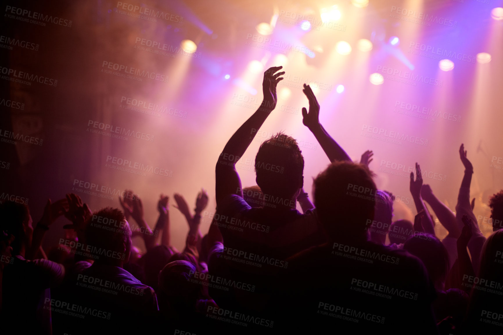 Buy stock photo Rear view of a music fan dancing with her arms raised at a music concert