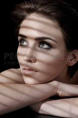 Buy stock photo A young woman with flawless skin and dark hair looking away against a dark background