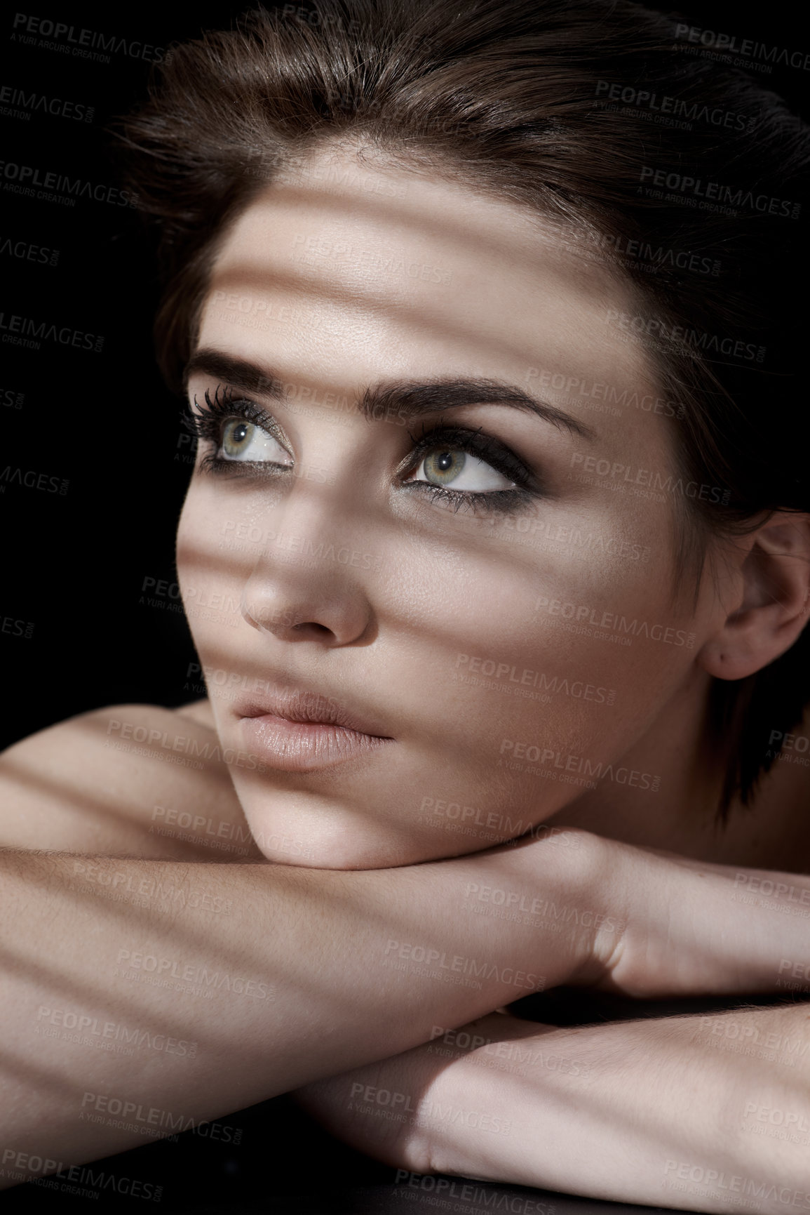 Buy stock photo A young woman with flawless skin and dark hair looking away against a dark background