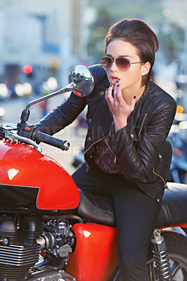 Buy stock photo A beautiful young biker looking at herself in her bike's mirror