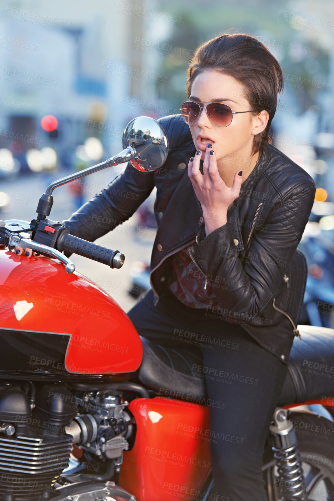 Buy stock photo A beautiful young biker looking at herself in her bike's mirror