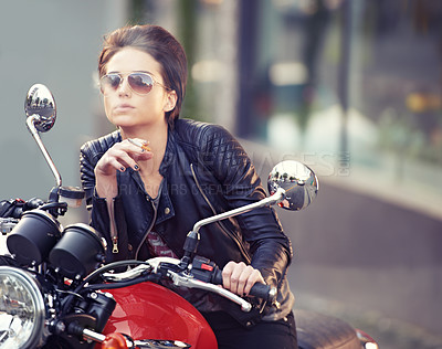 Buy stock photo Shot of a young female biker smoking a cigarette