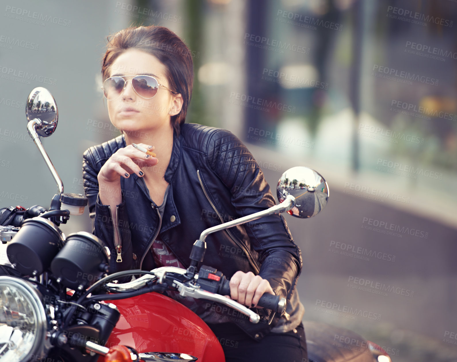 Buy stock photo Shot of a young female biker smoking a cigarette