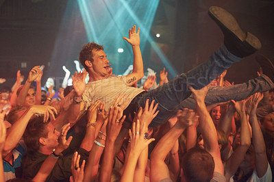Buy stock photo Music, party and crowd surfing with man at concert for rock, celebration and festival. Energy, light and dance with audience listening to live band show performance at disco, summer break and dj