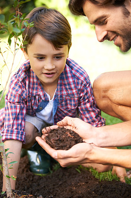 Buy stock photo A father showing his son soil full of earthworms while they're out gardening