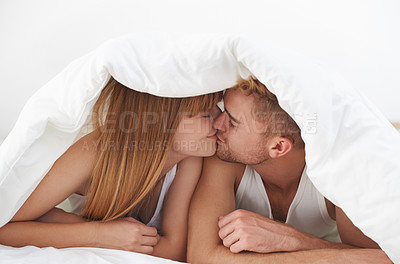 Buy stock photo Shot of an affectionate couple kissing under the covers