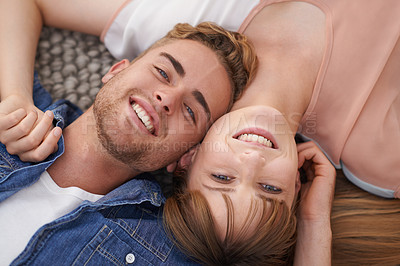 Buy stock photo A young couple lying on the living room floor close together with affection