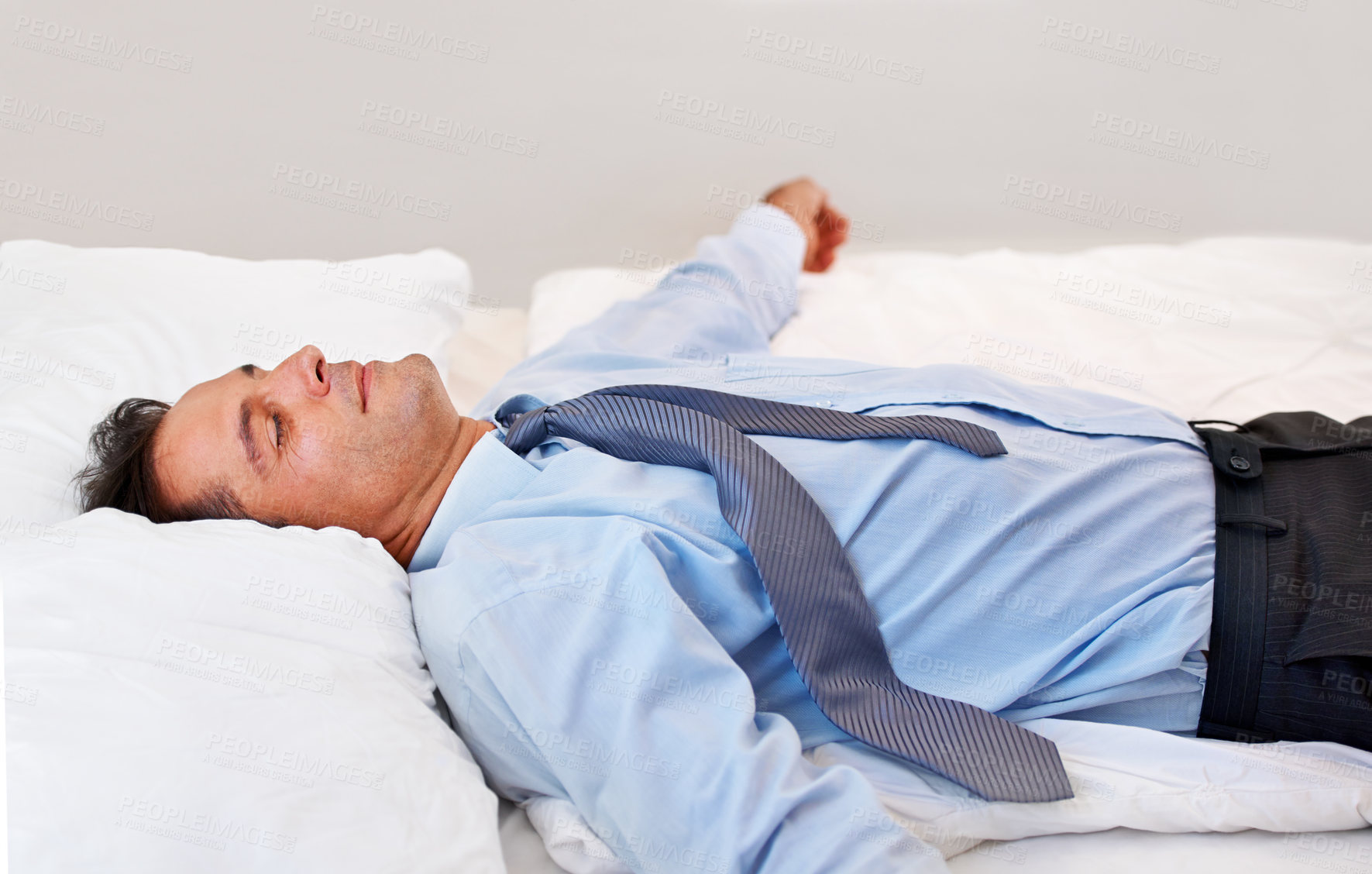 Buy stock photo A businessman lying on his bed absolutely exhausted
