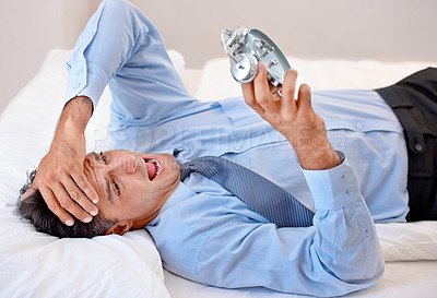 Buy stock photo Businessman, alarm clock and stress for waking up in bed, anxiety and late for business. Male person, frustrated and annoyed for time at home, professional and sleepless or lazy and worry in bedroom