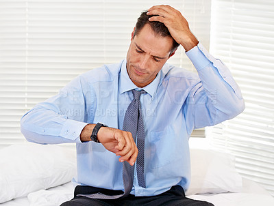 Buy stock photo A businessman looking at his wristwatch after sleeping in too long