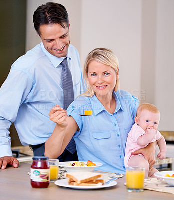 Buy stock photo Couple, eating and breakfast with baby, kitchen and home in morning, mother and spoon with food. Man, shirt and tie for job, accountant and corporate in field, care and love for family, career