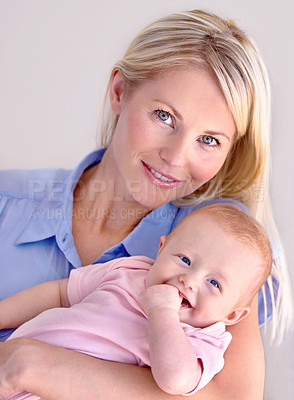 Buy stock photo Young mother holding her cute baby while smiling at the camera