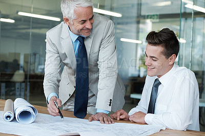 Buy stock photo Shot of two architects going over a building plan