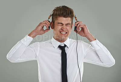 Buy stock photo Businessman, headphones and stress for music or audio, streaming radio and song on gray background. Male person, anxiety and listening to playlist or podcast, overwhelmed and frustrated with sound