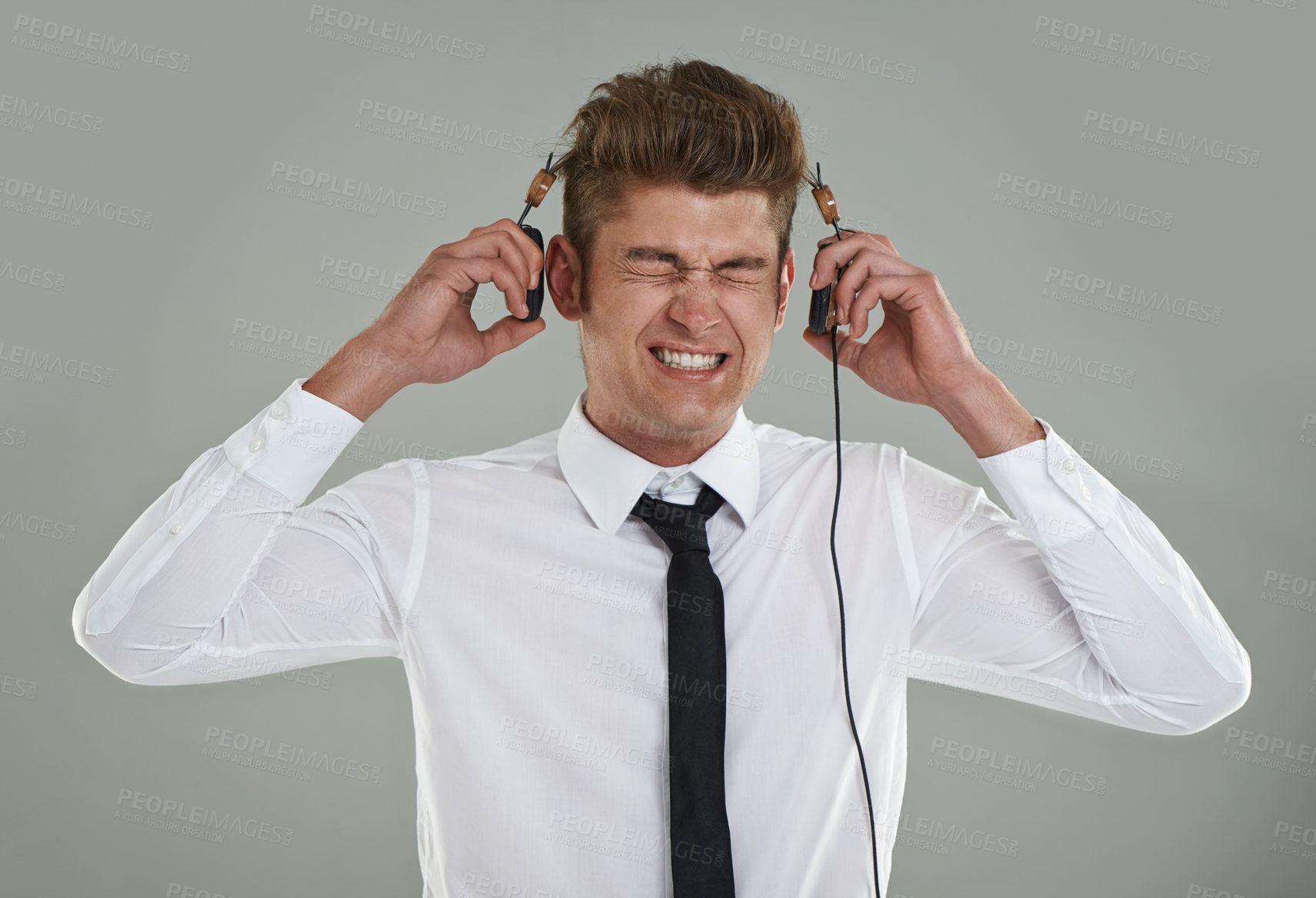 Buy stock photo Businessman, headphones and stress for music or audio, streaming radio and song on gray background. Male person, anxiety and listening to playlist or podcast, overwhelmed and frustrated with sound