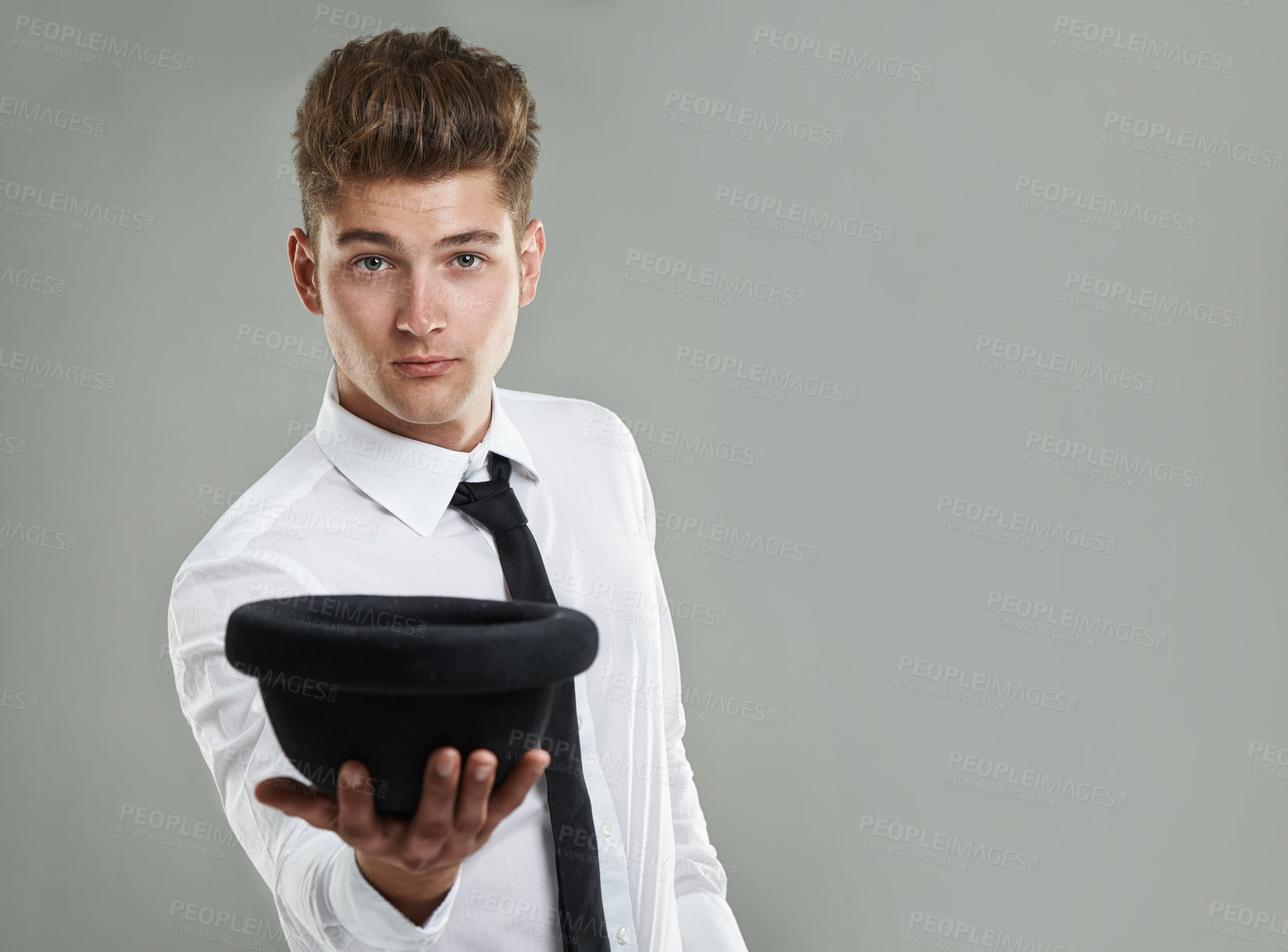 Buy stock photo A young hipster holding his hat out while posing in studio