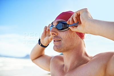 Buy stock photo Cropped closeup shot of a man wearing swimming goggles looking out at the ocean