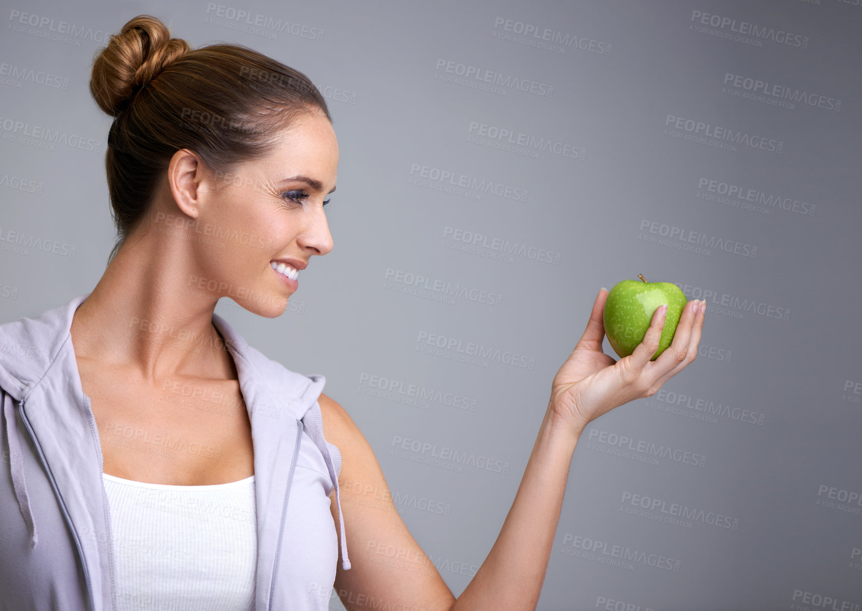 Buy stock photo Happy, health and woman in studio with apple, offer or mockup for fiber or gut health on grey background. Nutrition, space and model with fruit for weight loss help, nutrition or raw superfoods diet