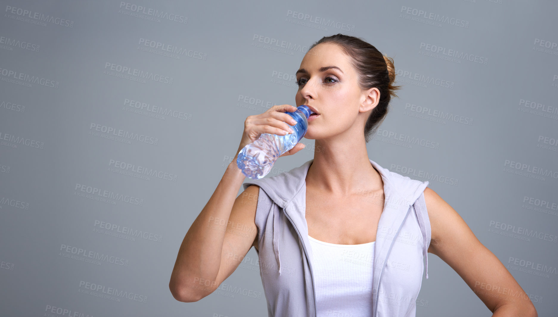 Buy stock photo Woman, fitness and drinking water for hydration or natural sustainability on a gray studio background. Face of thirsty female person or athlete with mineral drink in rest, break or recovery on mockup