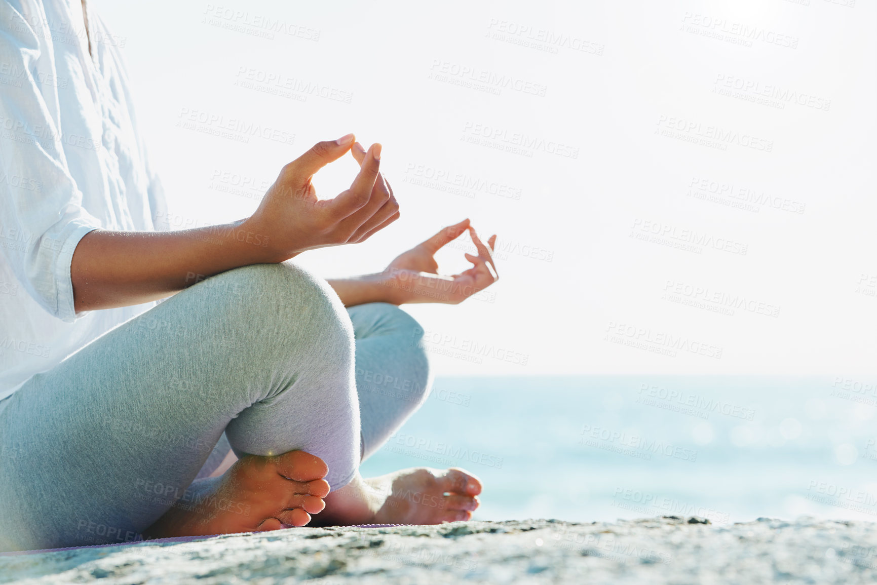 Buy stock photo A young woman performing a yoga routine on the beach in the summer sun