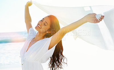 Buy stock photo Beautiful young woman holding up a linen cloth as the wind catches it