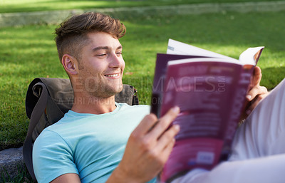 Buy stock photo Man, student and book on grass for reading, smile and ideas with learning for development at campus. Person, studying and happy with scholarship, information and knowledge for education at college