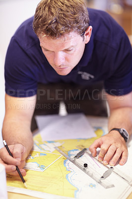 Buy stock photo Cropped shot of a handsome young male lifeguard finding co-ordinates on a map in their office
