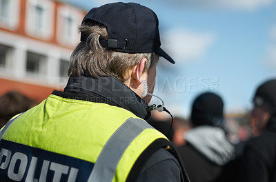 Buy stock photo Law enforcement, protection or crowd control with police officer in city for peace, safety and authority. Emergency services, justice and guard with back of person in street at rally, order or arrest