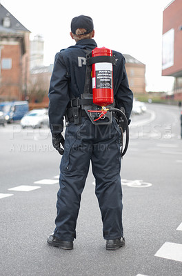 Buy stock photo Emergency, police and man safety officer or fireman working a neighborhood street feeling fearless and ready for service. Security, legal and rearview of law enforcement person in a urban town