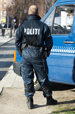 Buy stock photo Police man, van and security in the city of Denmark for street safety, service or law enforcement patrol. Back of male officer standing ready to fight crime for justice or riot control in urban town