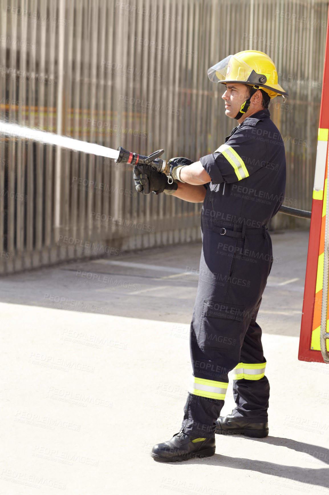 Buy stock photo Male firefighter, spray water and emergency worker with helmet, uniform and brave to stop inferno. Fireman, fire hose and fearless on mission to rescue, health and safety service   at job outdoor