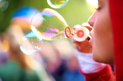 Buy stock photo A young woman blowing bubbles outside - profile
