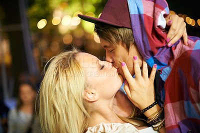 Buy stock photo A young couple kissing at an outdoor event