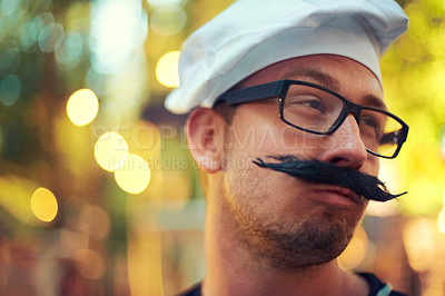 Buy stock photo Man, fake mustache and beret in chef costume with comic face, creative and confident in french baking. Young person, glasses and cooking job in bokeh and culinary education in pastry art in europe