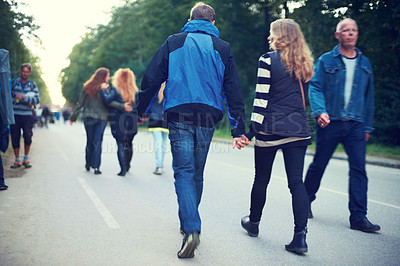 Buy stock photo Couple, back and holding hands while walking among trees and crowds along road in New Zealand. Rear view of man, woman and people for travel, date and bonding in busy woods, park and highway