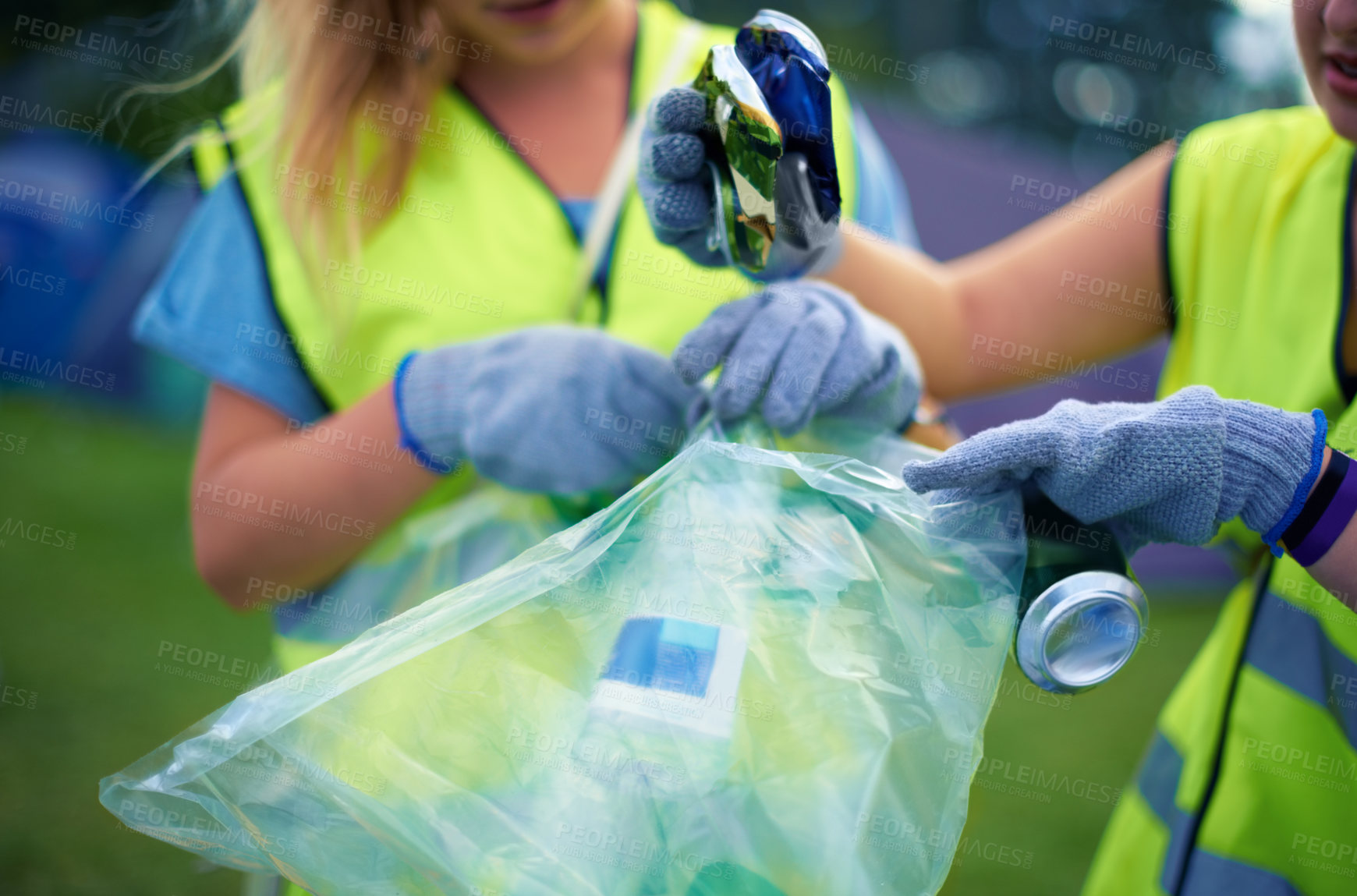 Buy stock photo Cropped shot of two young women picking up trash after a festival