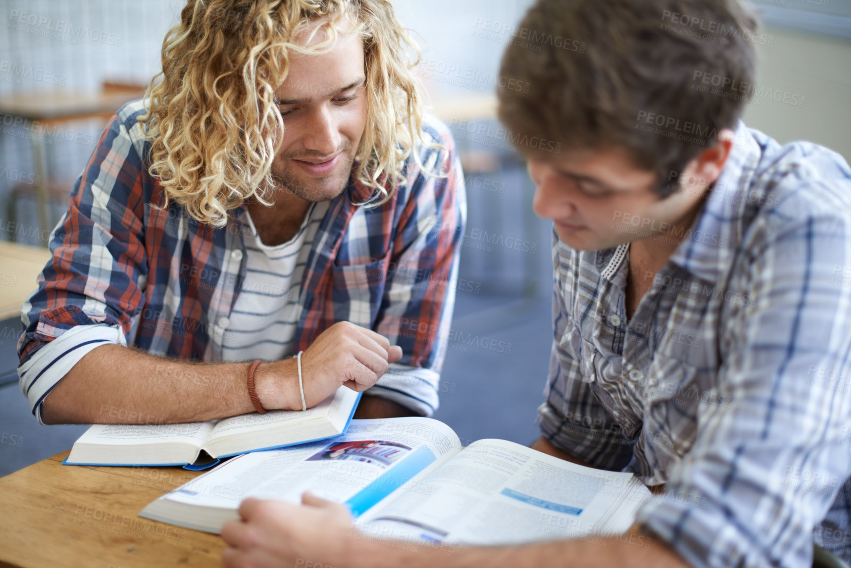 Buy stock photo Shot of two male students studying together in class