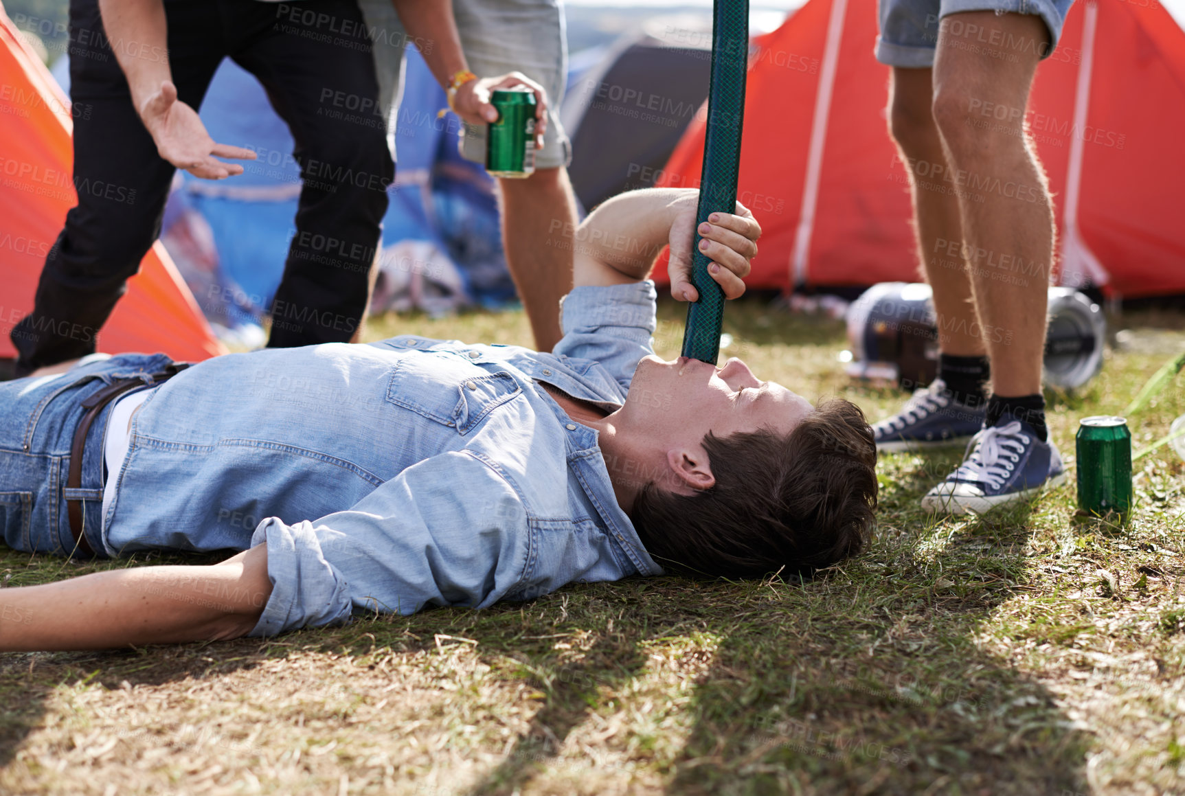 Buy stock photo Alcohol, drinking and funnel with man at festival, on ground for event, party or social gathering. Beer, grass and young drunk person with friends on grass or field outdoor at camp for celebration