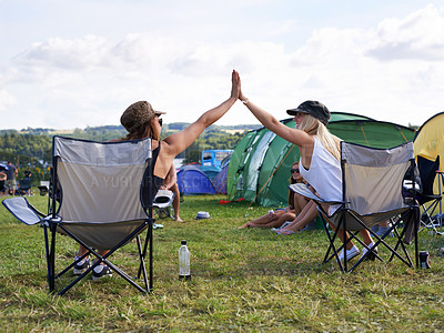 Buy stock photo Rearview shot of two friends giving each other a high five at an outdoor festival