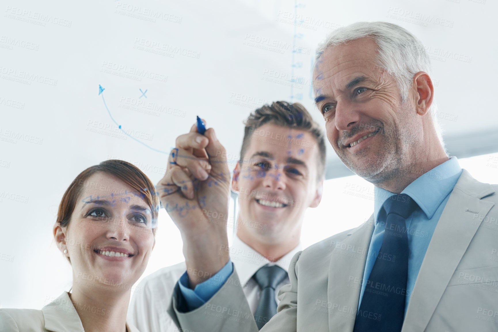 Buy stock photo Shot of businesspeople brainstorming on glass wall in an office