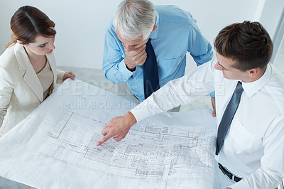 Buy stock photo Shot of a three businesspeople going over blueprints