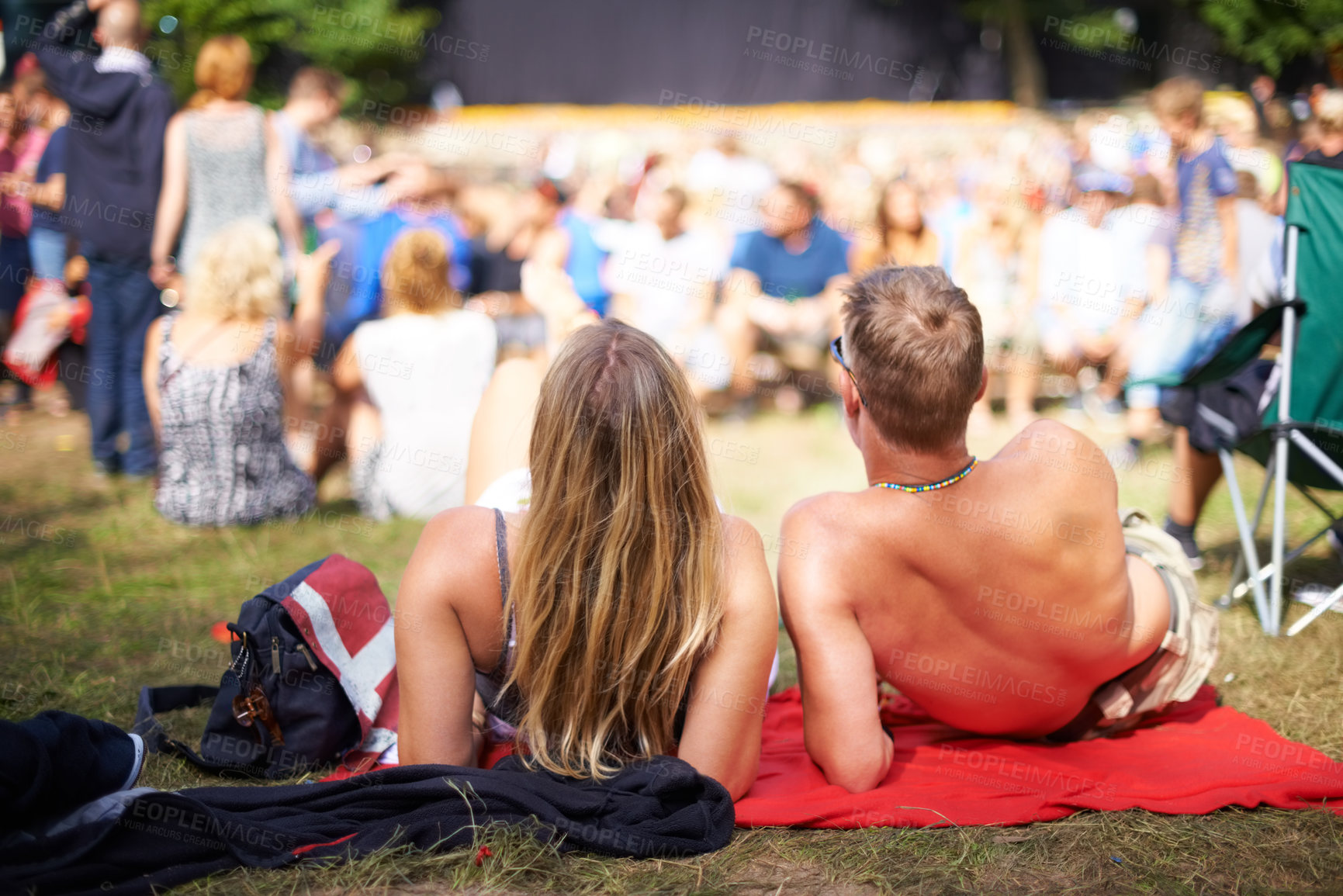Buy stock photo Couple, crowd and concert for festival, love and date with summer, nature and quality time. Man, woman and audience with sunshine, music and stage in park with romance, relationship and happiness