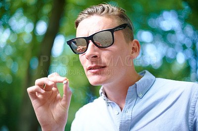 Buy stock photo Sunglasses, man and smoking weed outdoor at event, celebration and music festival alone. Cigarette, marijuana and face of young person at party, carnival and concert in nature with cannabis joint