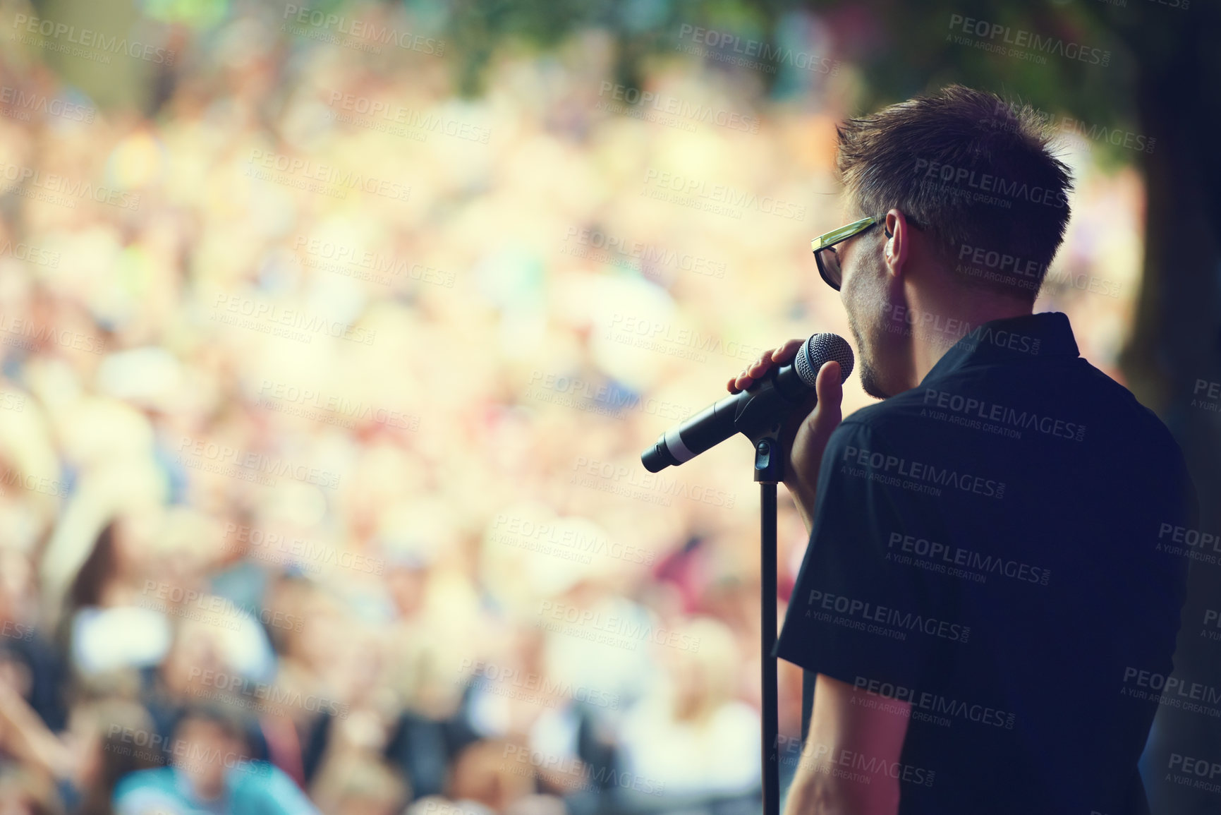 Buy stock photo Music, microphone and concert with man at festival for rock, performance and party in nature. Celebration, energy and audience with male singer on stage for club, rave and dj event in outdoors