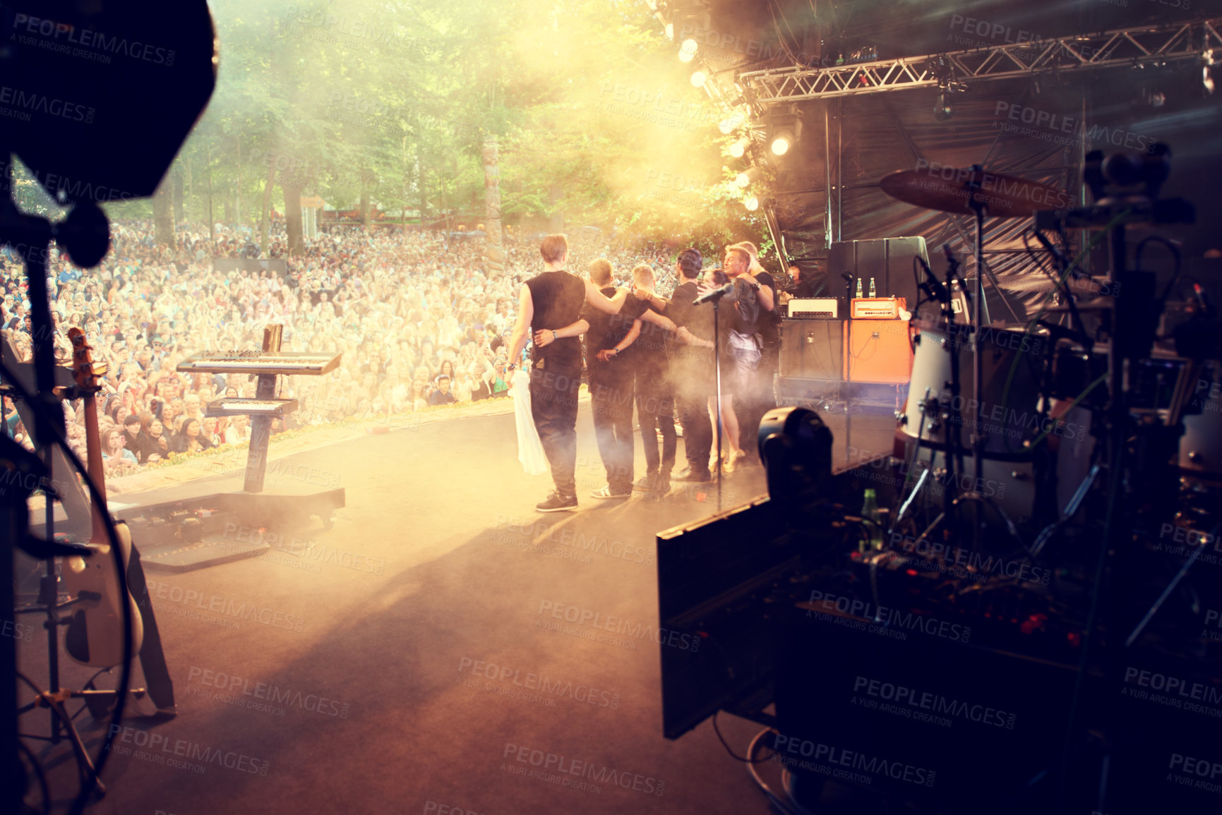 Buy stock photo A popular band hugging and looking out into the crowd after a successful gig